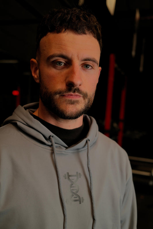 Male wearing anatomise pebble grey hoodie in gym from side