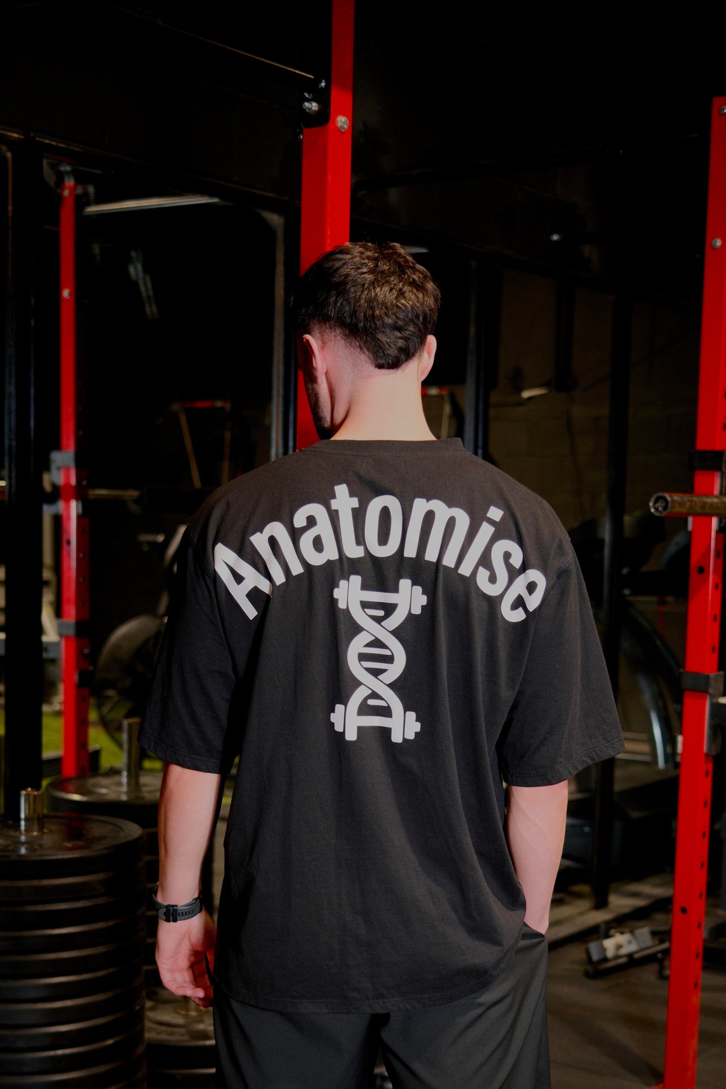 Male wearing anatomise black oversize t-shirt in gym from back